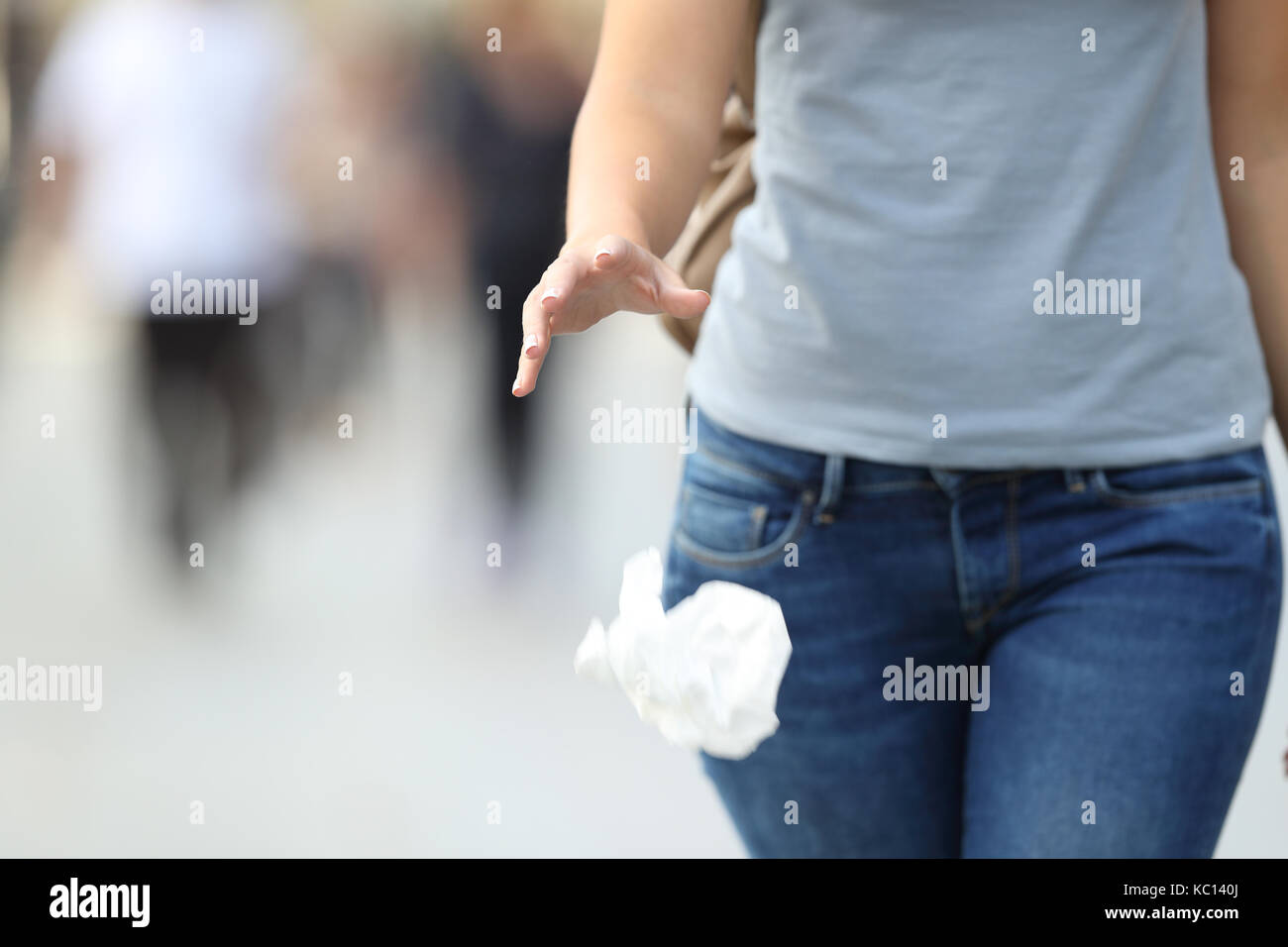 Close up of an irresponsible behavior of a woman throwing garbage to the floor while walking on the street Stock Photo