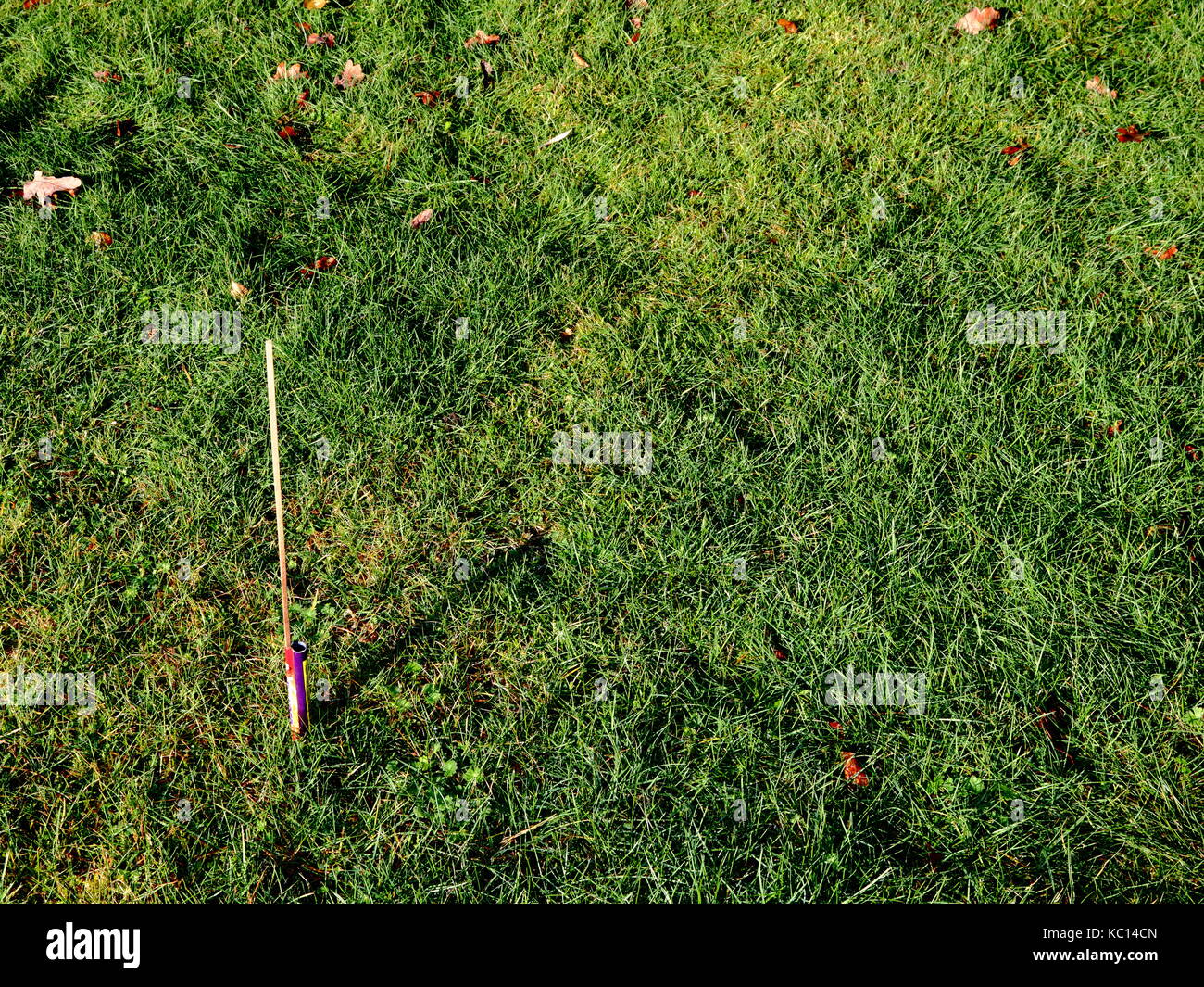 Morning after the Night Before! Spent domestic display rocket firework embedded in lawn with long shadow on new year's day! Stock Photo