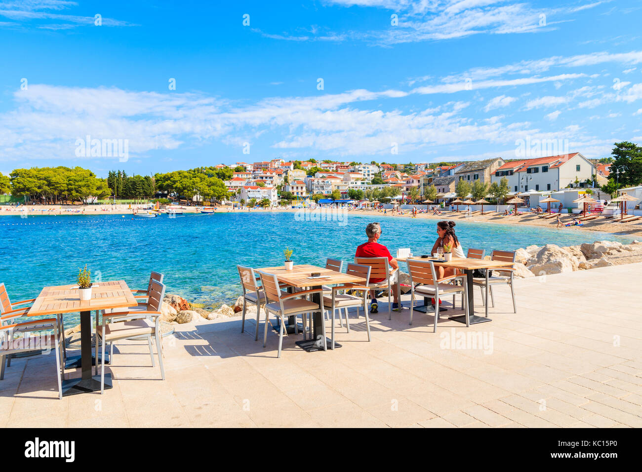 PRIMOSTEN, CROATIA - SEP 5, 2017: Couple of tourists sitting in seaside bar in Primosten town enjoying summer vacation, Dalmatia, Croatia. Stock Photo
