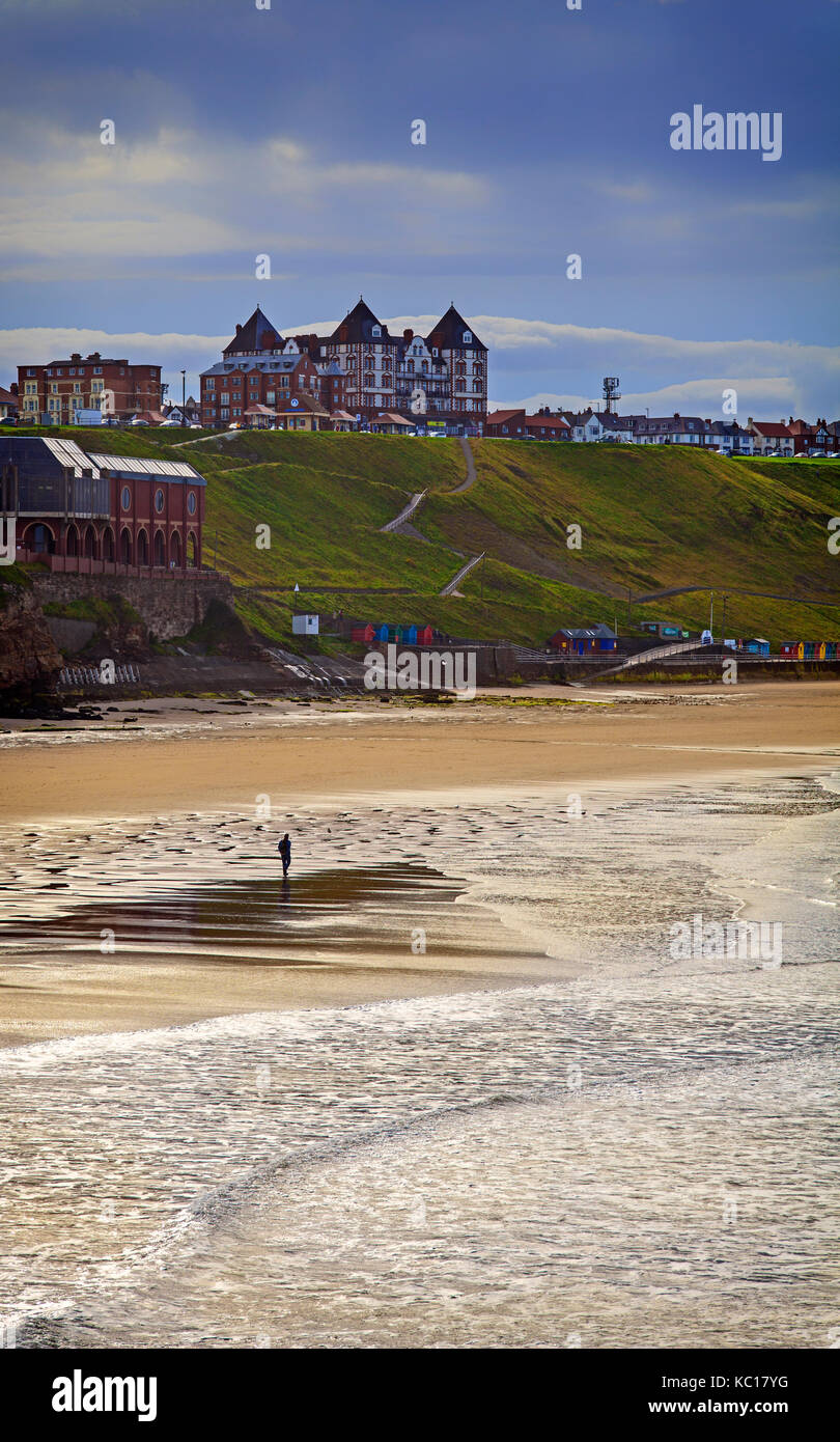 Solitary walker on the North Beach overlooked by the Metropole Luxury Apartments on the West Cliff area of Whitby, Yorkshire, England Stock Photo