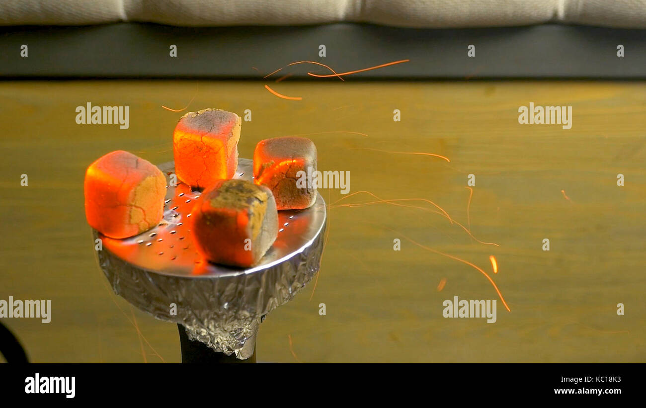 Sparks from the burning coals hookah. Hookah tobacco in bowl. Blazing  red-coconut charcoal. Preparing the shisha, aka nargile or hookah at a  restaurant by placing the charcoals on top Stock Photo -