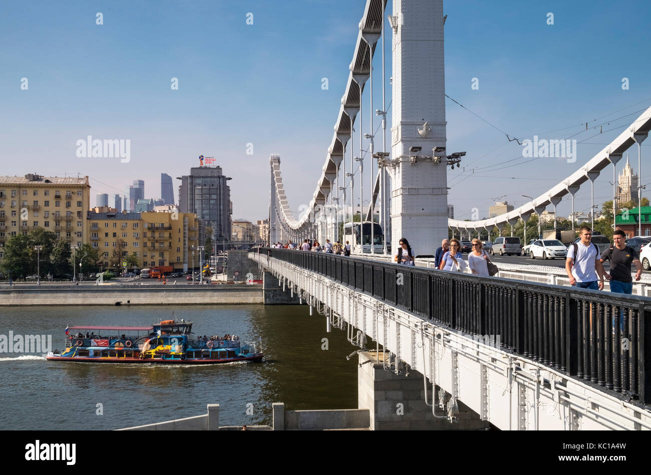 People and cars crossing Krymsky Bridge (Crimean Bridge) over the Moskva river, looking west towards Frunzenskaya nab, Moscow, Russia. Stock Photo
