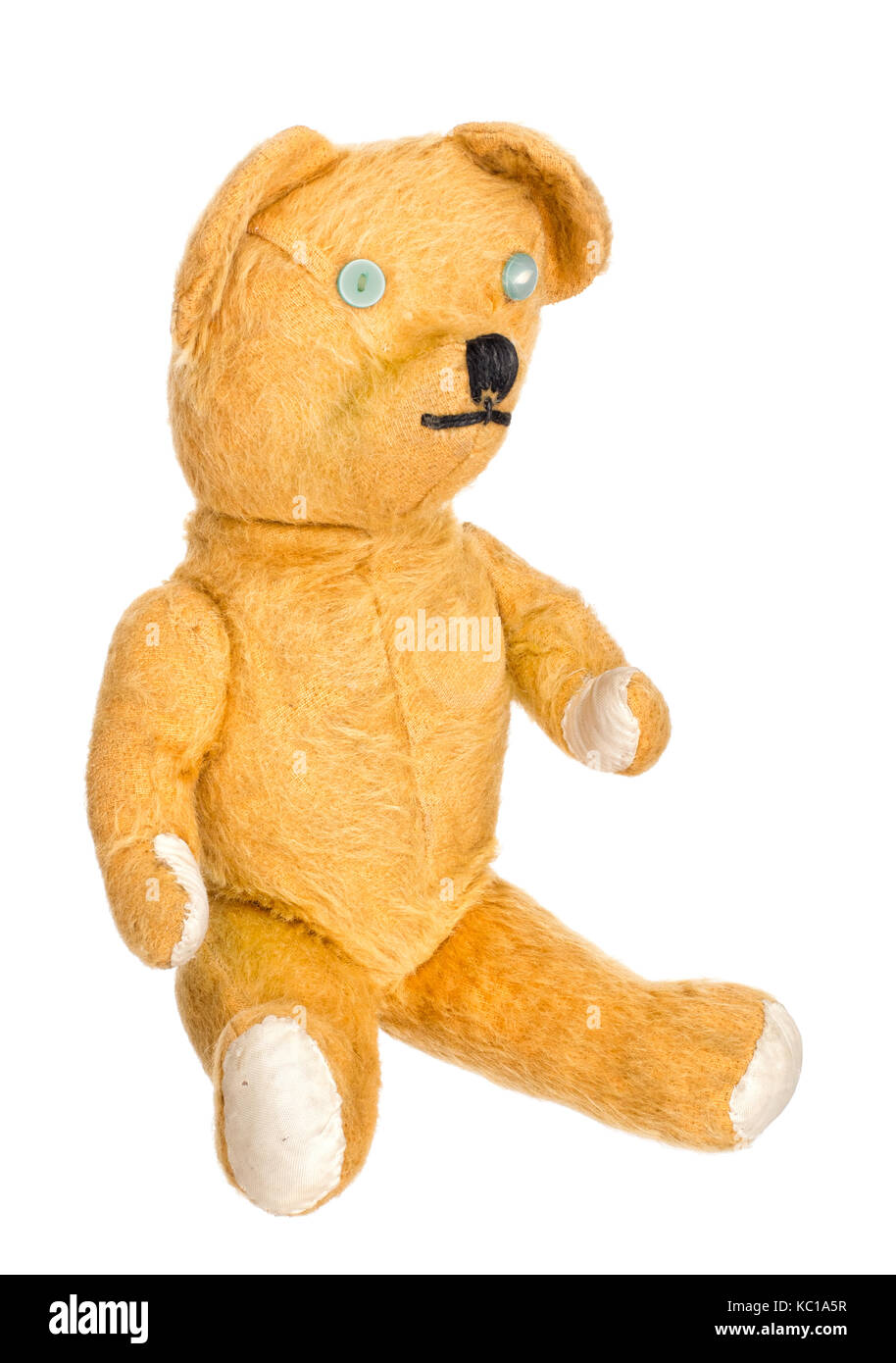Old, much loved, much repaired, unbranded toy teddy bear isolated. Stock Photo