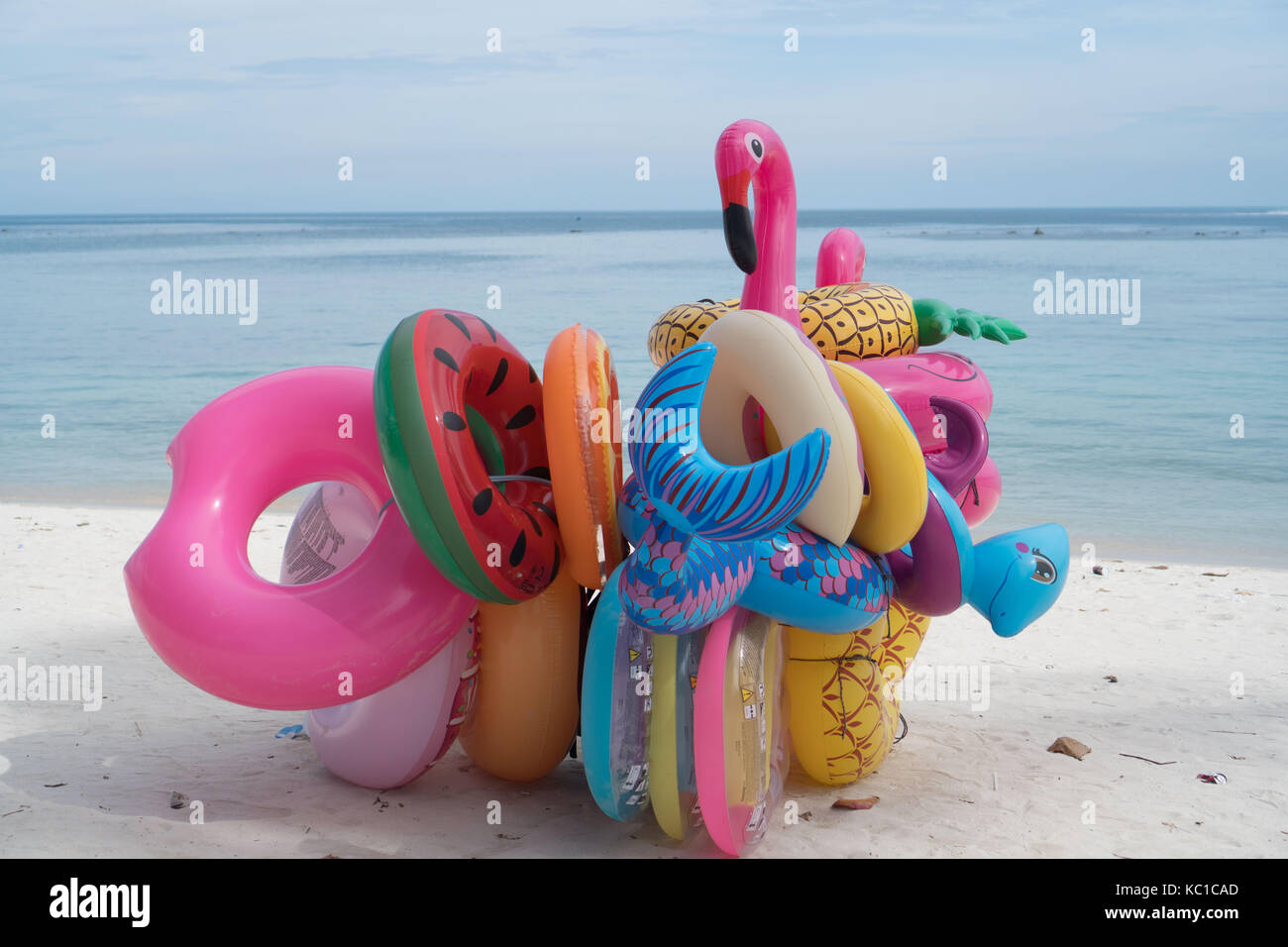 Bunch of many colorful inflatable toys isolated on the sandy beach over ...