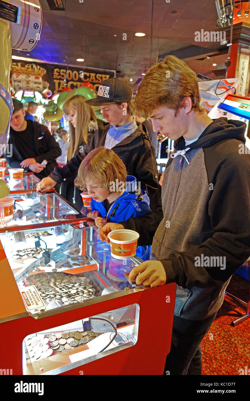 young children and teenagers playing gambling games in an amusement arcade on the golden mile, blackpool, england, uk. Stock Photo
