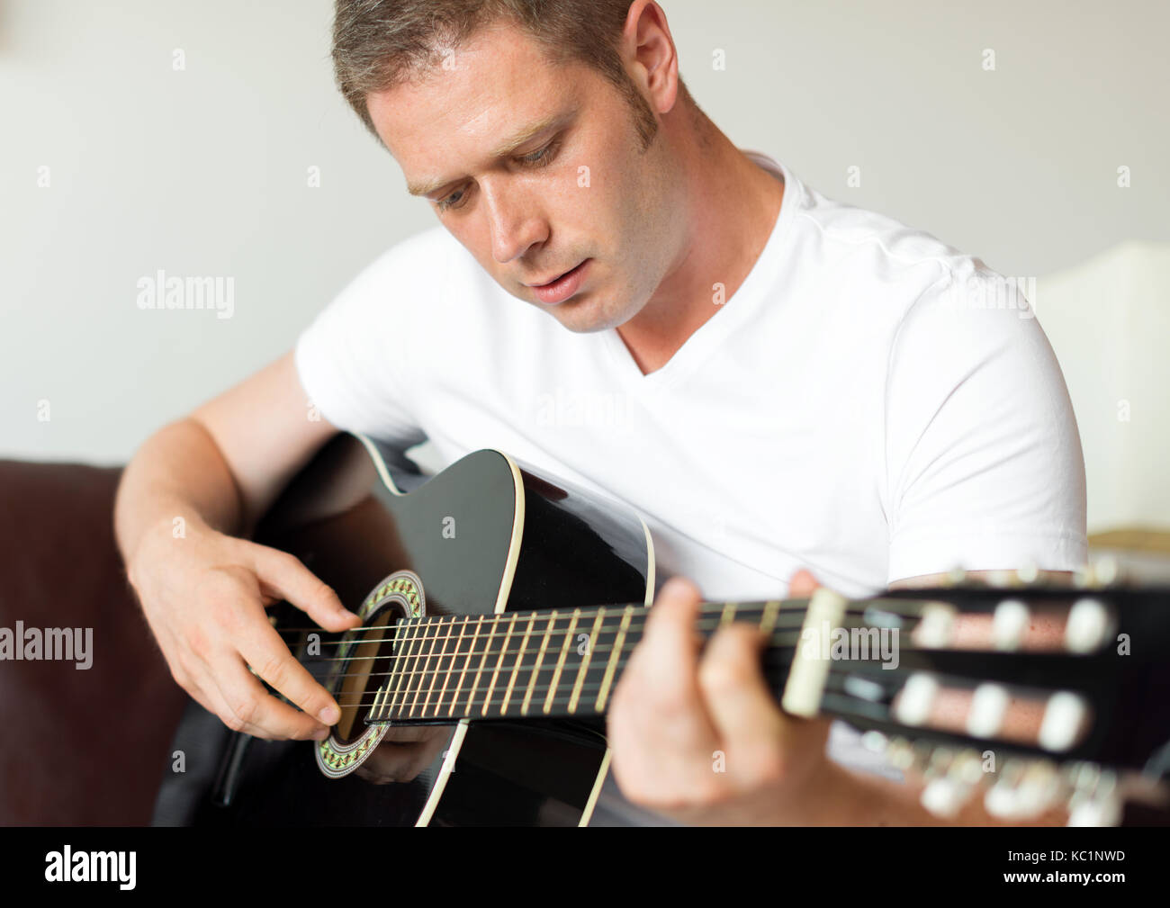 Handsome man playing guitar at home Stock Photo - Alamy