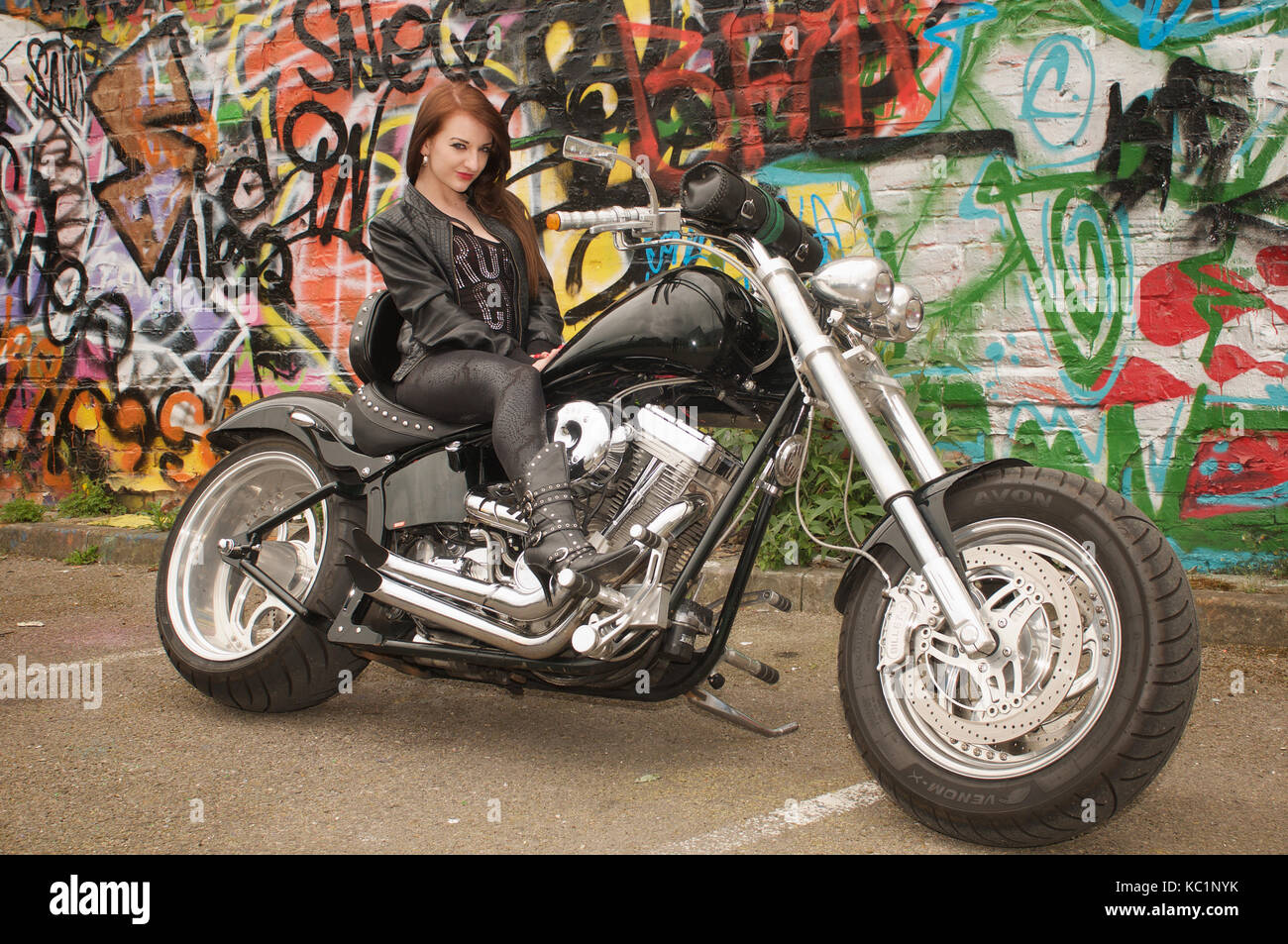 Pretty girl on a custom built chopper motorcycle in an urban location Stock Photo
