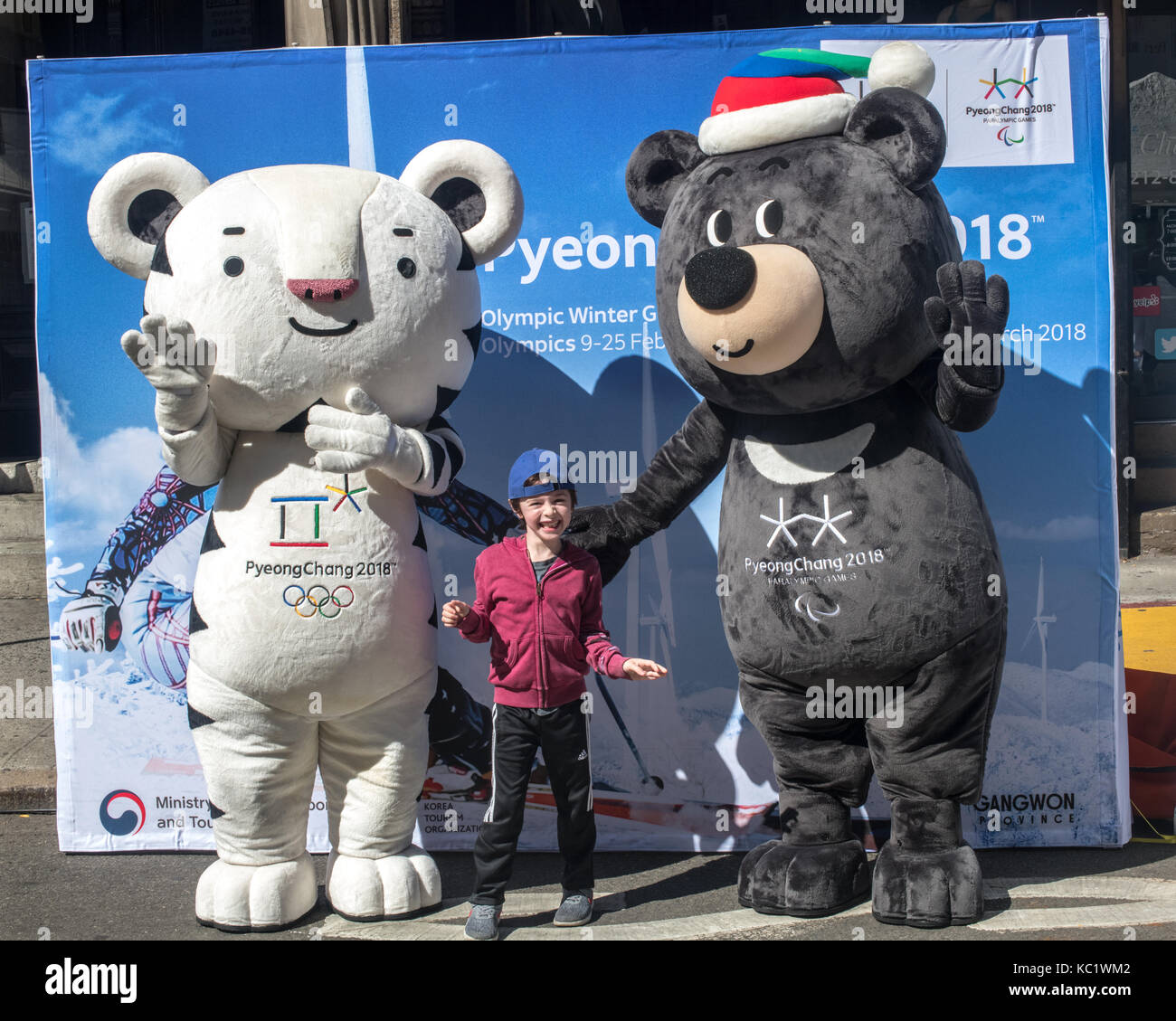 New York, USA, 1 October 2017. A kid poses with Soohorang (L) and Bandabi, the official mascots of the PyeongChang 2018 Winter Olympic and Winter Paralympic Games at a street fair in New York.  Soohorang is a symbol of strength and trust, and Korea's guardian animal - the white tiger symbolizes protection to all the athletes and spectators at the 2018 Winter Games. Bandabi is a symbol of strong will and patience, and of the host province of Gangwon. The Asiatic black bear embodies the spirit of the paralympics. Photo by Enrique Shore/Alamy Live News Stock Photo