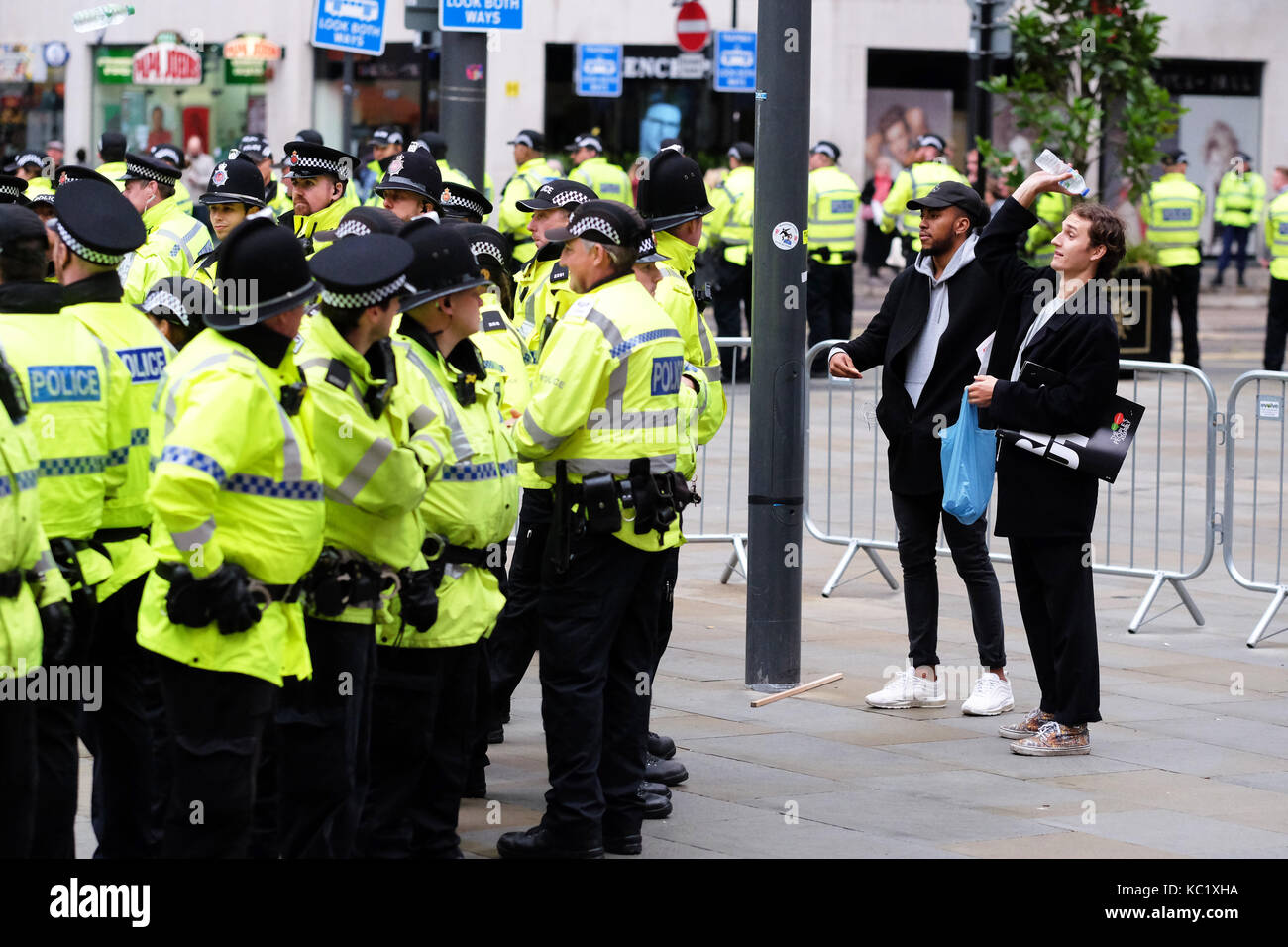 St Peters Square, Manchester, UK - Sunday 1st October 2017 - An anti government protester prepares to pass a bottle of water into a small group of fellow protesters who have been surrounded and kettled by Police just outside the Conservative Party Conference. Photo Steven May / Alamy Live News Stock Photo