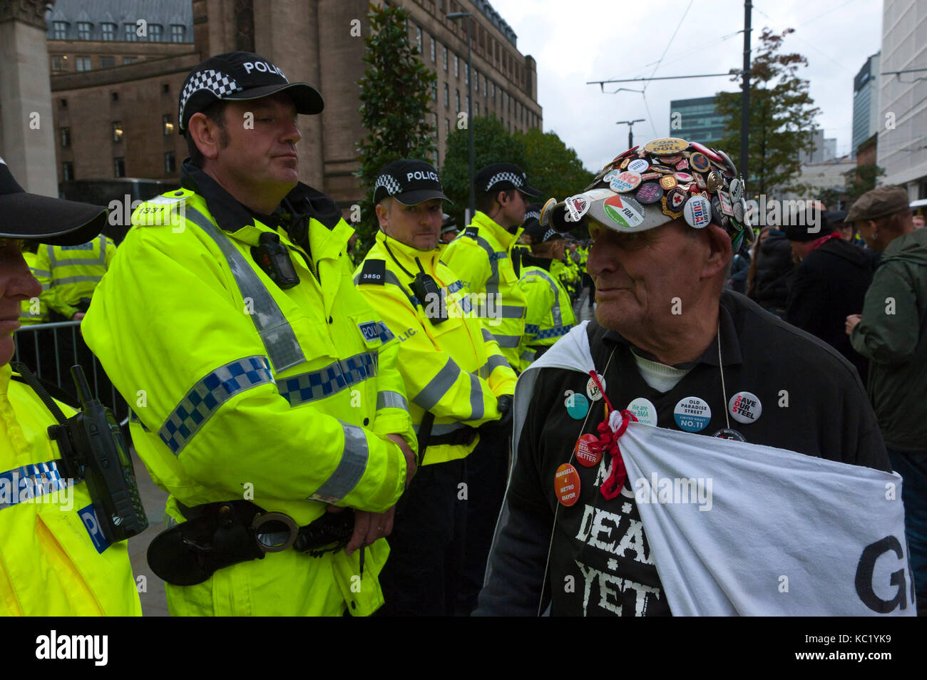 Manchester, UK. 1st October, 2017. Retired carpenter & joiner eighty-three-year-old Terry Hutt from Camden, London, walks a line of police officers near the Tory Party Conference Centre. Terry is an activist for DAN - Direct Action network. Ant-Fracking activists and dusabled anti Tory activists meet heavy police security at St Peter's Square near the Conference Centre. Pro-peace, anti-austerity, anti-war protests, including rallies, public meetings, comedy, music, & culture, take place during the four days of the Conservative Party Conference in Manchester, UK. 1st - 4th Oct 2017. The protes Stock Photo