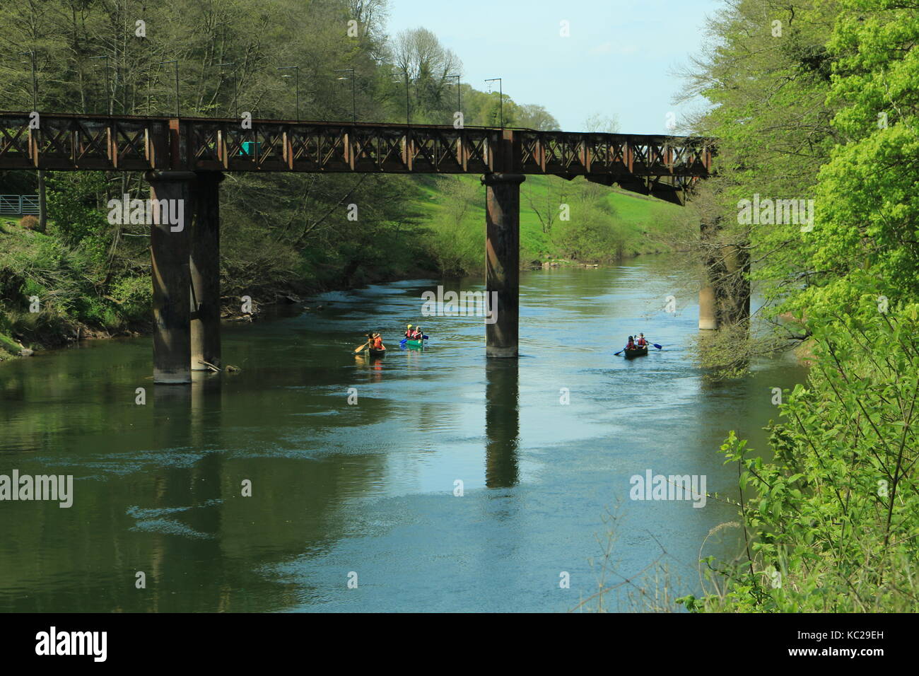 Railway bridge over the River Wye at Redbrook. A group of open canadian canoeist traveling underneath Stock Photo