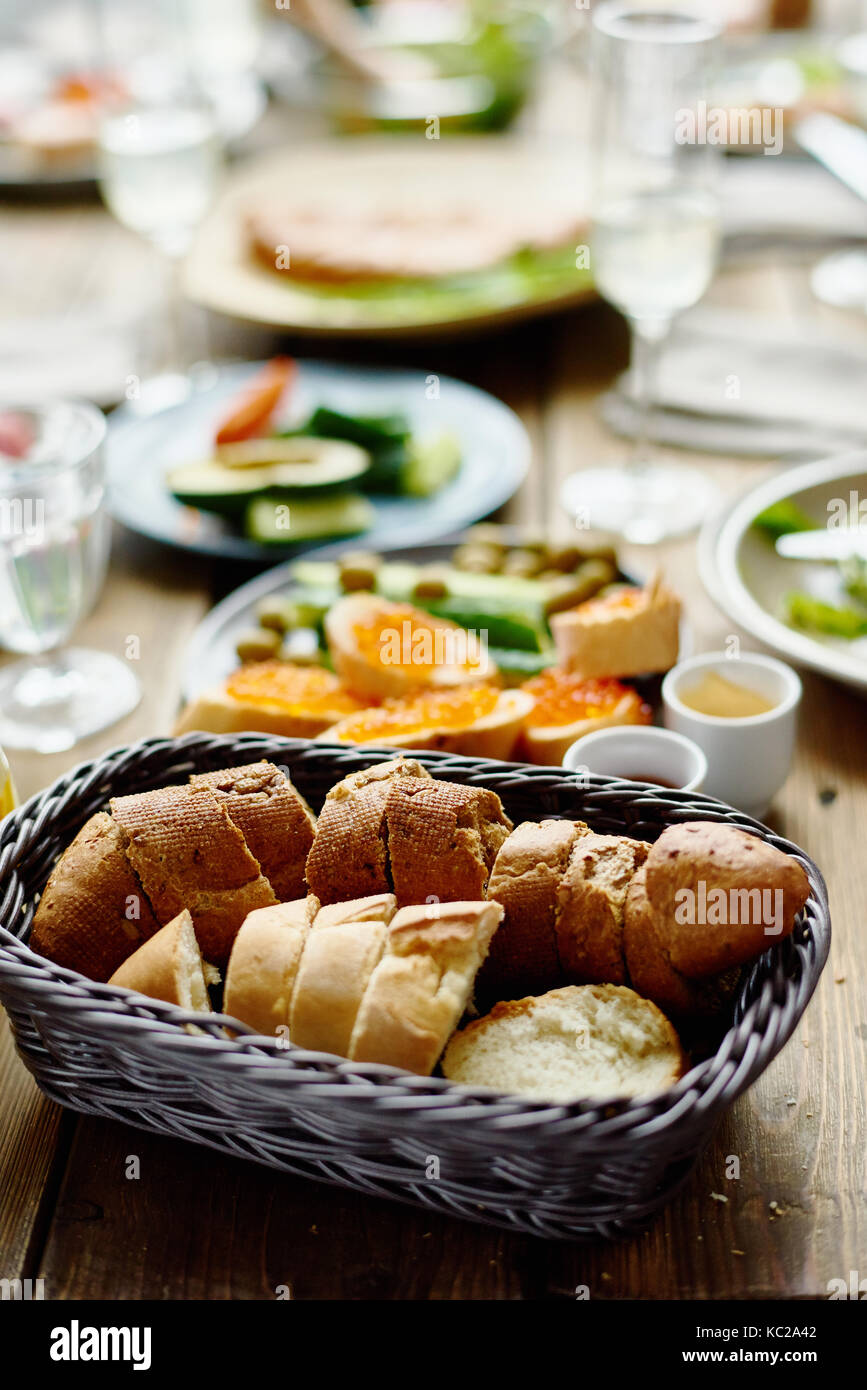 Closeup of bread basket on wooden dinner table with delicious food ready for the feast, no people Stock Photo
