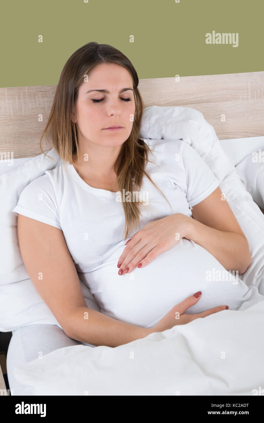 Young Pregnant Woman With Eyes Closed Sitting On Bed Stock Photo Alamy