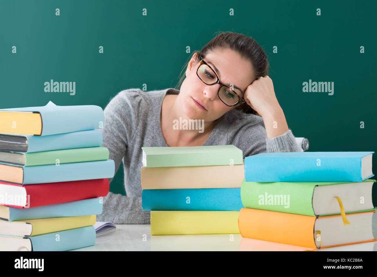 Young Tired Woman Sitting With Stack Of Books In Classroom Stock Photo ...