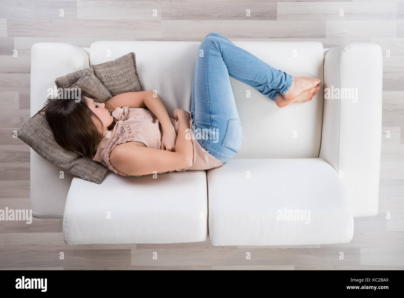 High Angle View Of Young Woman Napping On Sofa Stock Photo