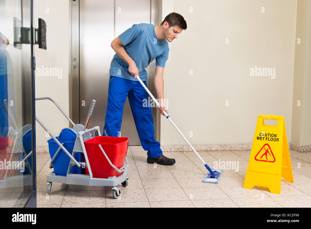 Happy Male Janitor With Cleaning Equipments Mopping Floor Stock Photo Happy Male Janitor With Cleaning Equipments Mopping Floor Stock Photo