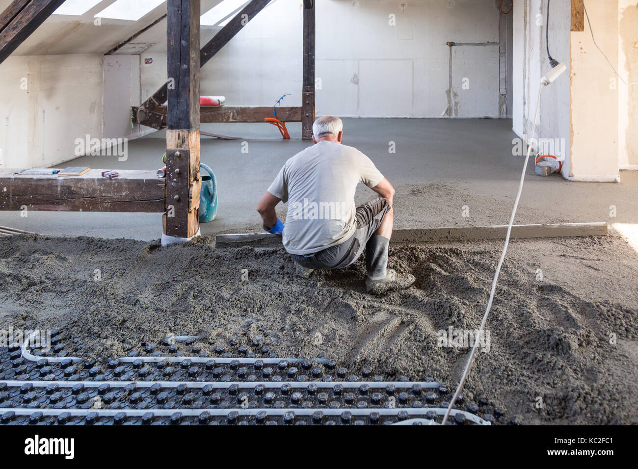 Laborer leveling sand and cement screed over floor heating Stock Photo