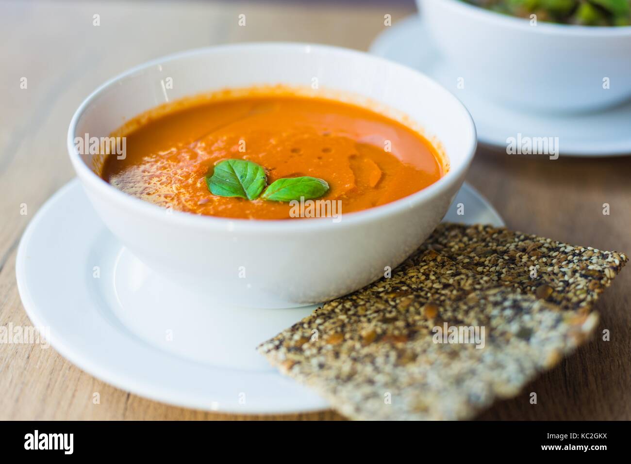 Fresh creamy tomato soup with basil in plate on wooden table Stock ...