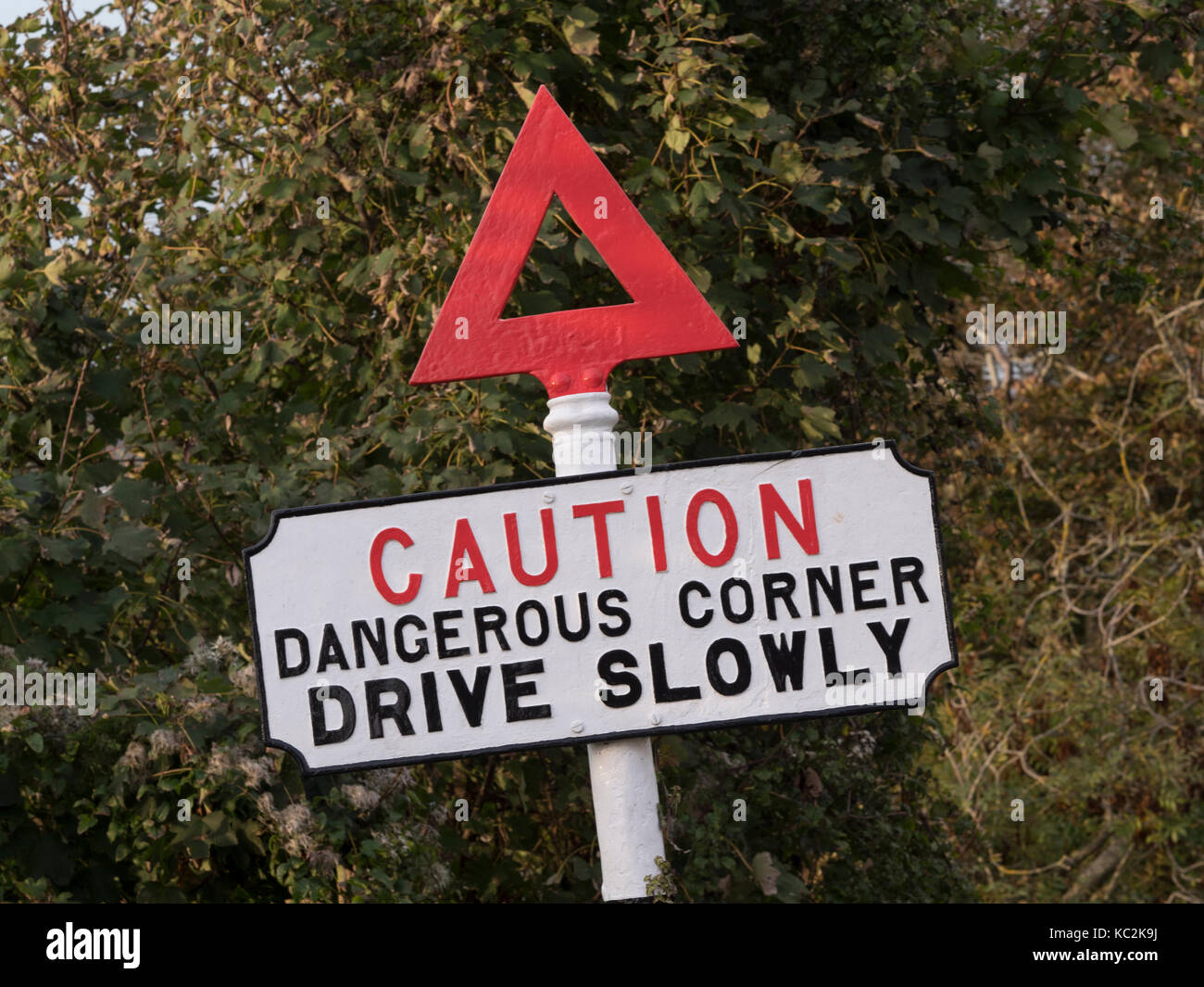 Vintage road traffic warning sign - caution dangerous corner drive slowly - England, UK Stock Photo