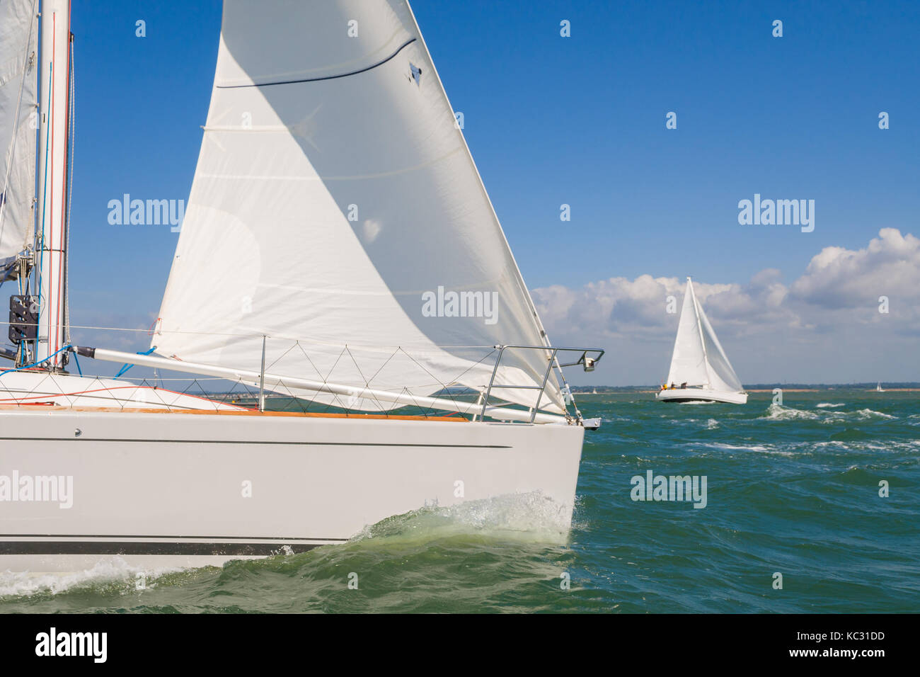 Two beautiful white yachts or sail boats sailing or racing at sea on a bright sunny day Stock Photo