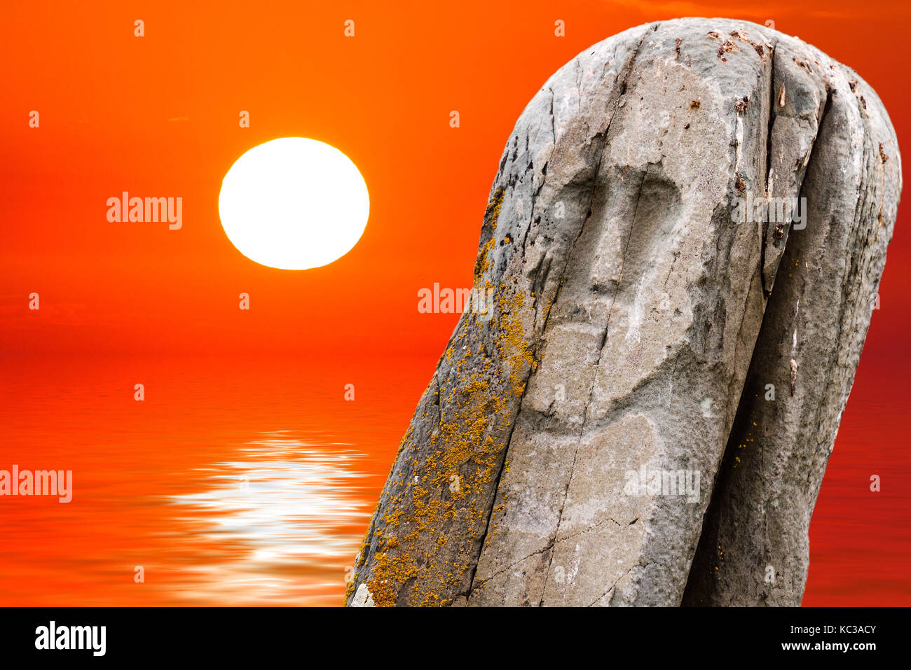 Ancient stone ritual tribe totem (idol) with orange sea sunset or ...
