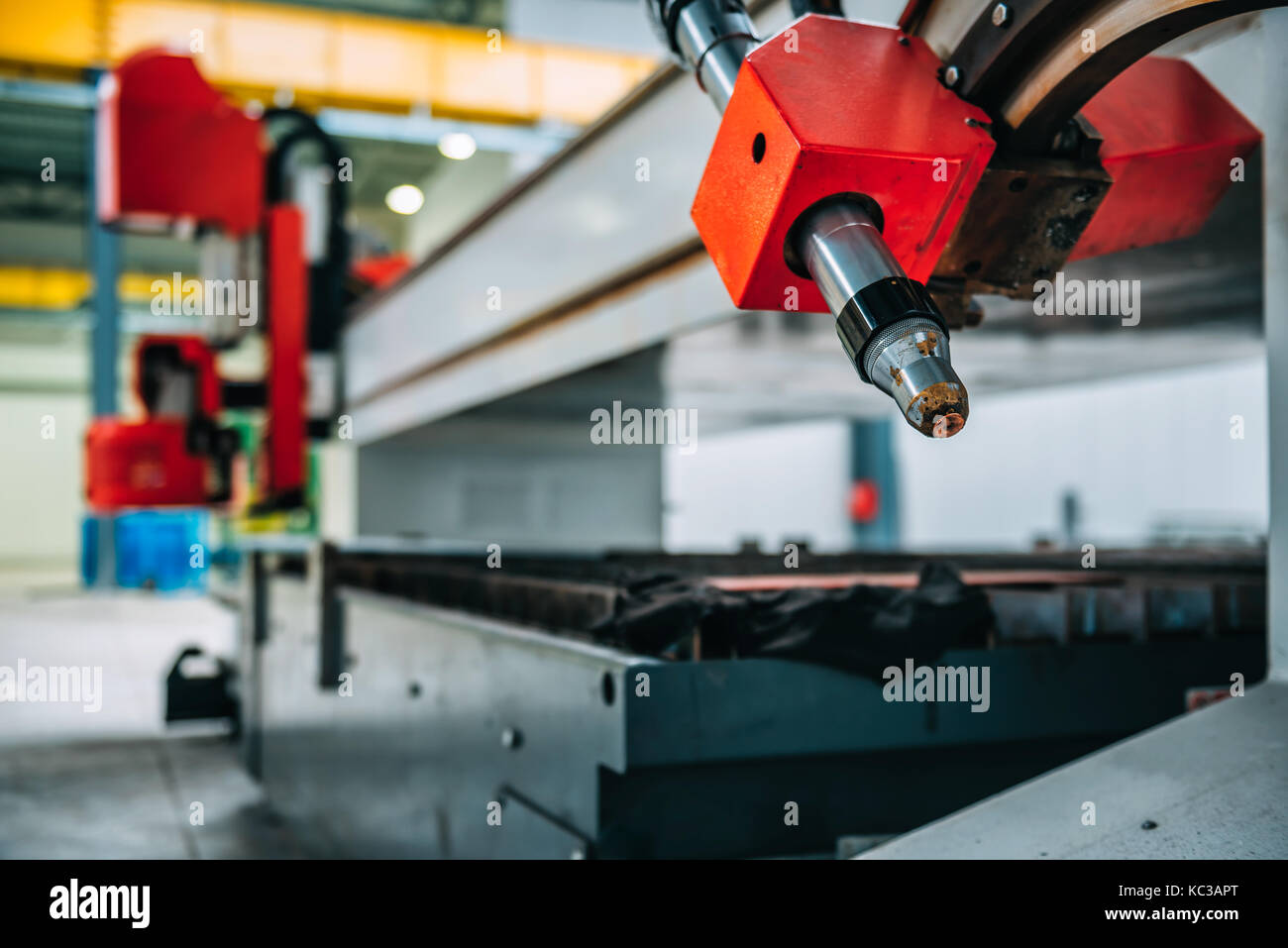 CNC Plasma cutter machine nozzle in big metal industrial hall Stock