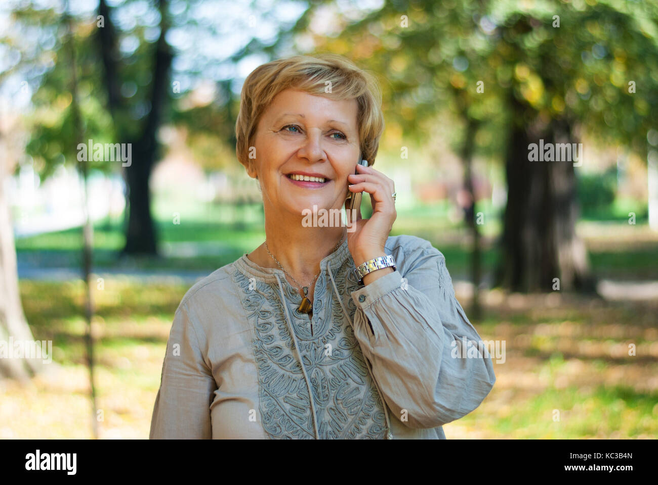 middle-aged woman talk on the mobile phone in the park Stock Photo - Alamy