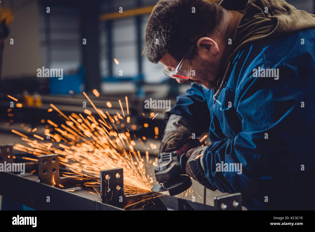 Worker Using Angle Grinder in Factory and throwing sparks Stock Photo