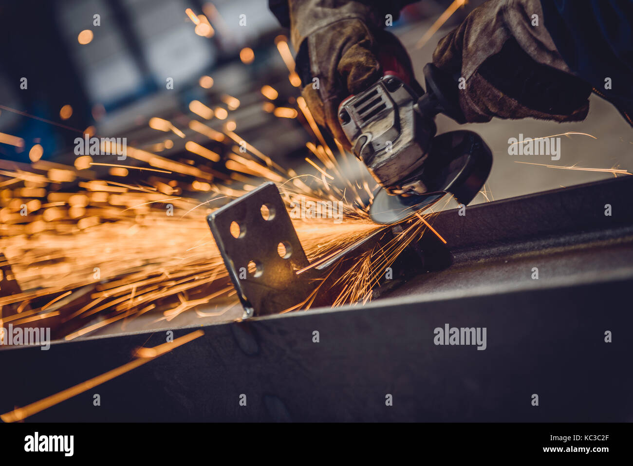 Worker Using Angle Grinder in Factory and throwing sparks Stock Photo