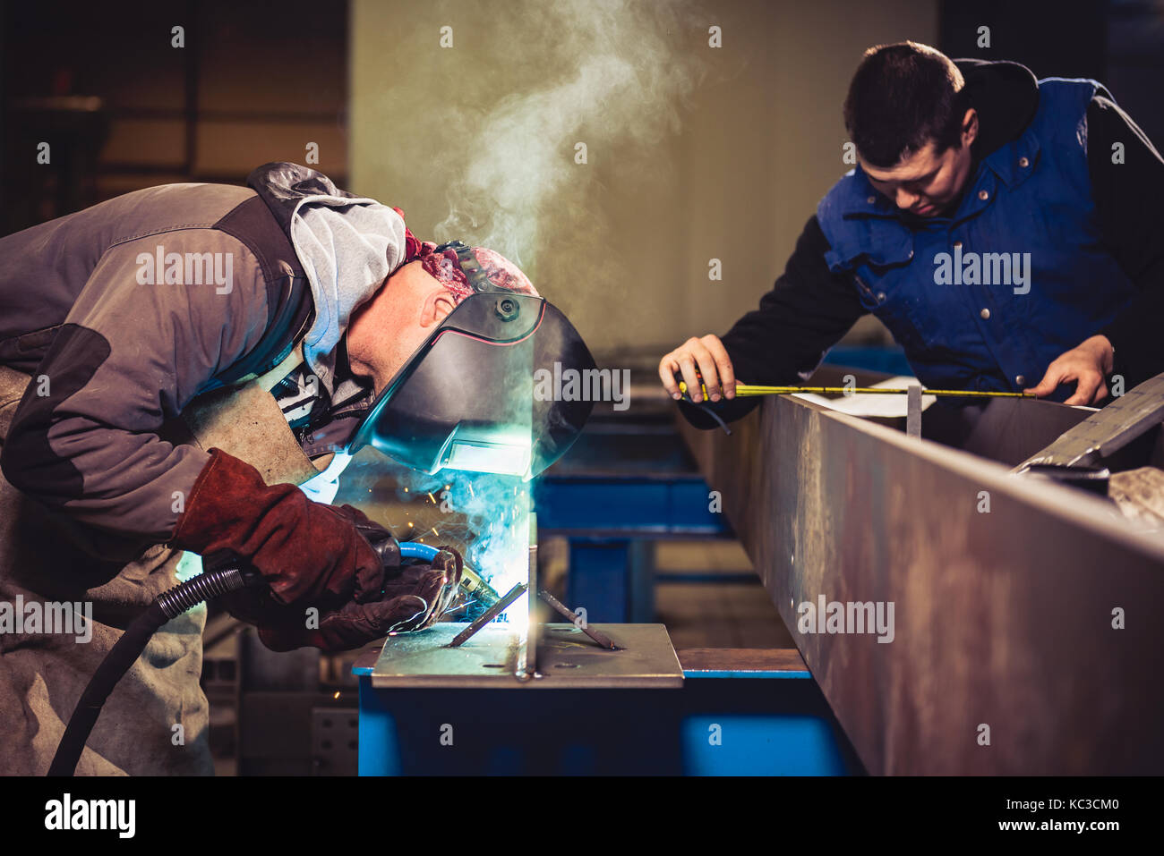 Industrial Welder With Torch and Protective Helmet in big hall welding