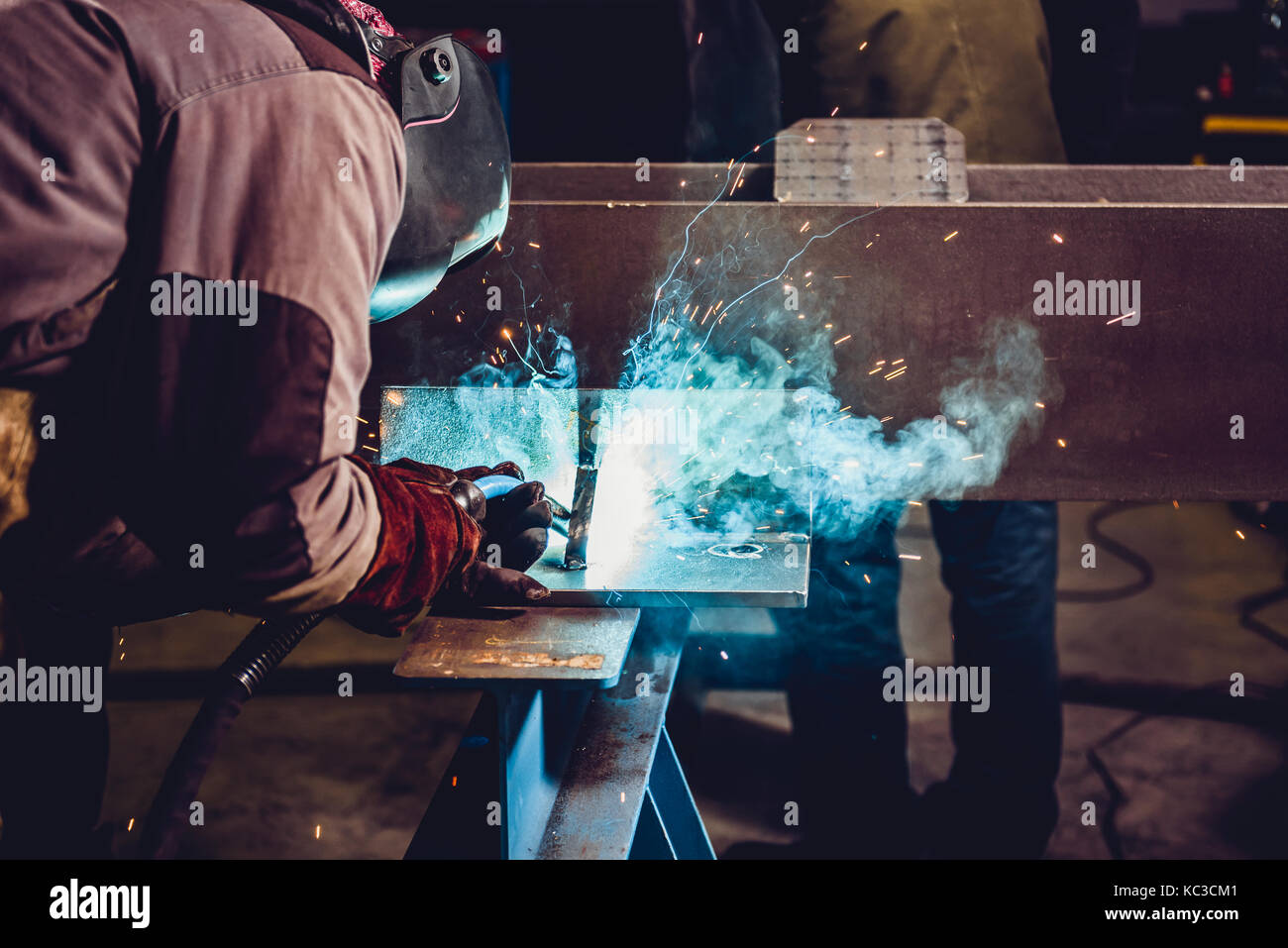 Industrial Welder With Torch and Protective Helmet in big hall welding
