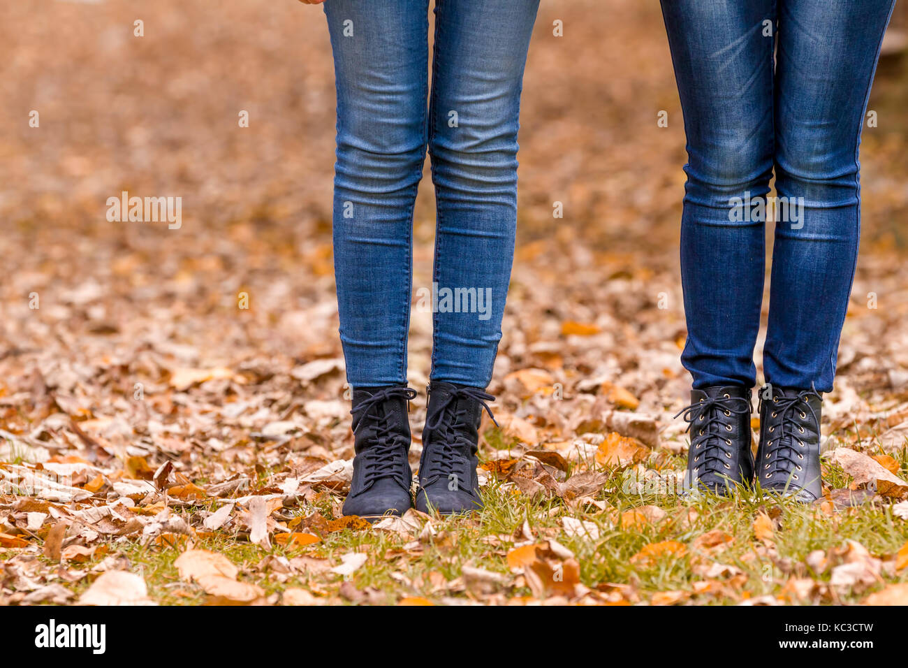 Girls feet boots walking on fall leaves outdoor with autumn season nature on background Stock Photo