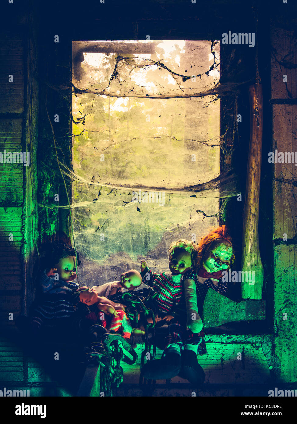 Photo of old dolls and an axe resting on an old window ledge covered in spiderwebs and dust. Stock Photo