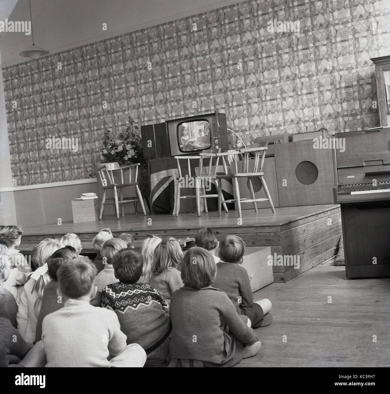 1964, historical, group of primary school children sit together watching a childrens programme on a new television set. it was at this time that childrens programming was first broadcast in the UK and the broadcasters gave away new TV sets to encourage viewing. Stock Photo