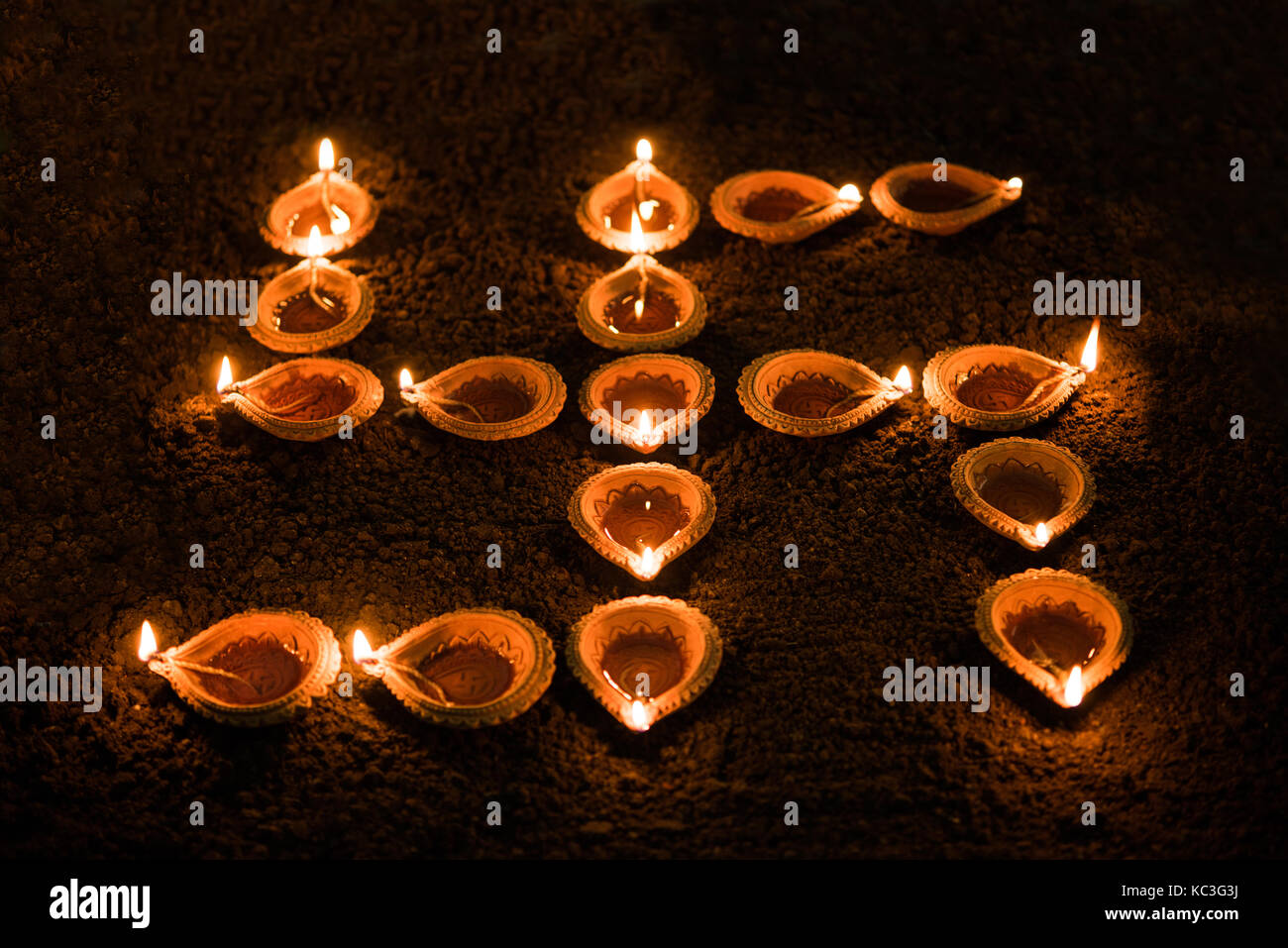 Diya and Swastik or Swastika - Swastika shape formed using diwali clay diya or oil lamps, selective focus Stock Photo