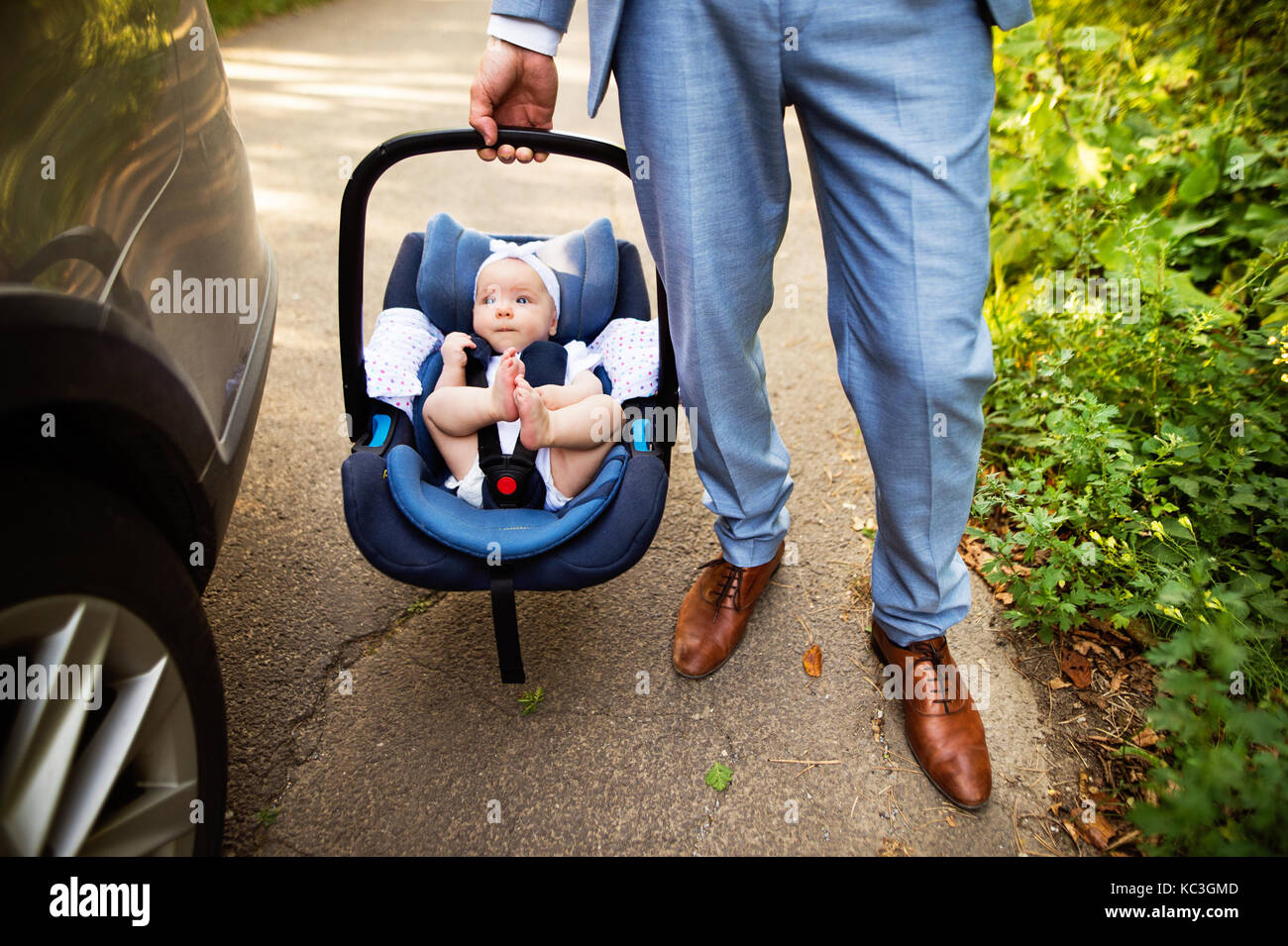 Unrecognizable man carrying his baby girl in a car seat. Stock Photo