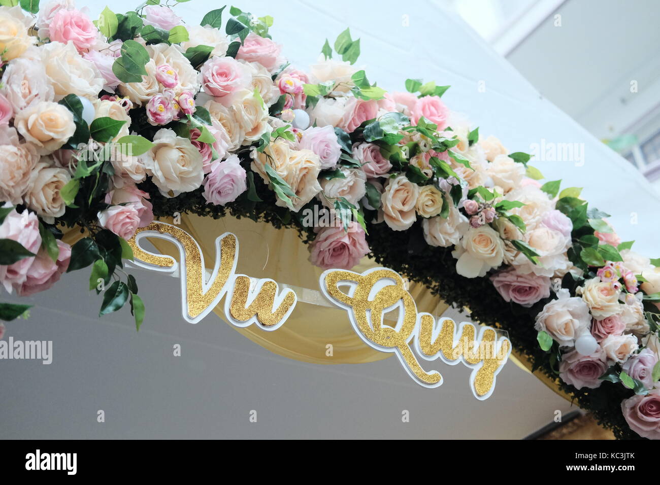 Gate made by flowers behind bride’s family. Text - Vu quy. Stock Photo