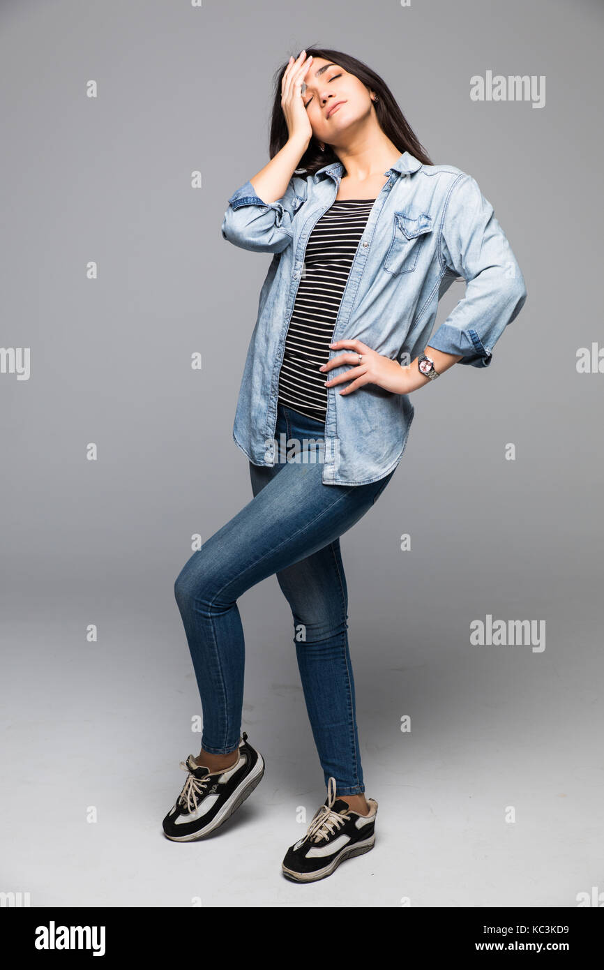 Young woman covering face with hand and looking at camera while ...