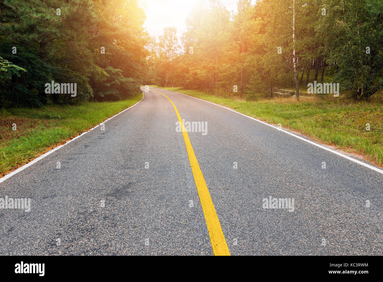 Empty country road with yellow line in the middle at sunset Stock Photo ...