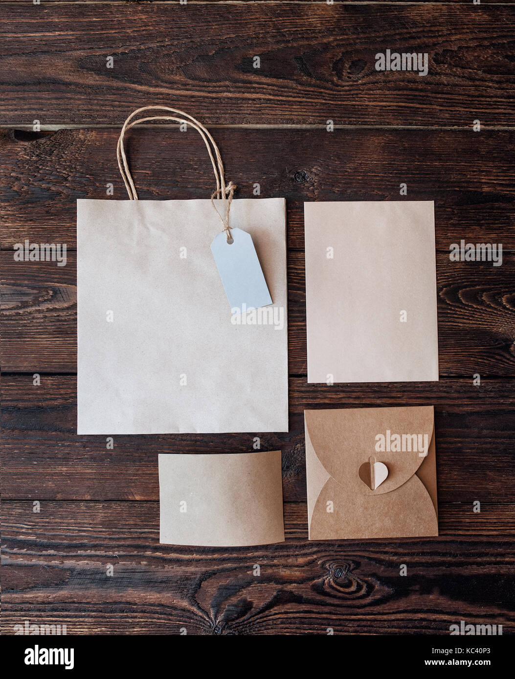 Mockup Paper bag from kraft paper with gift tag and Christmas gift boxes on a wooden background Stock Photo