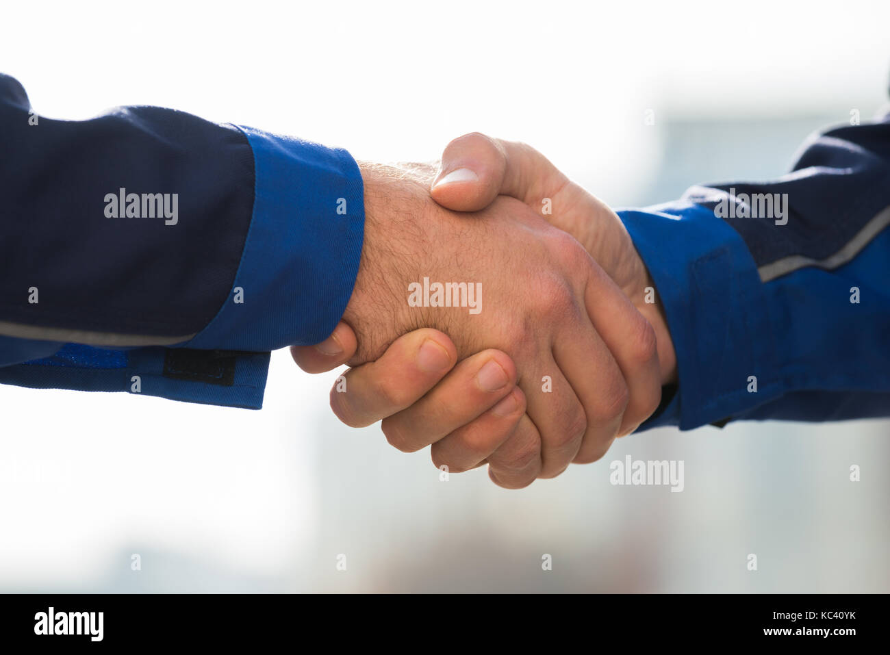 Cropped image of male architects shaking hands outdoors Stock Photo