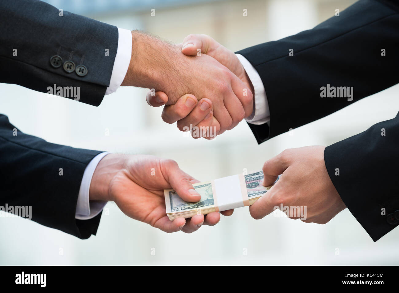 Cropped image of businessman shaking hand while bribing partner outdoors Stock Photo