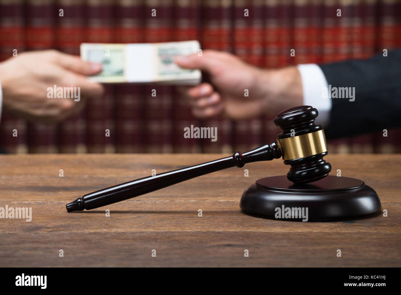 Gavel on wooden table with judge taking bribe from businessman in background at courtroom Stock Photo