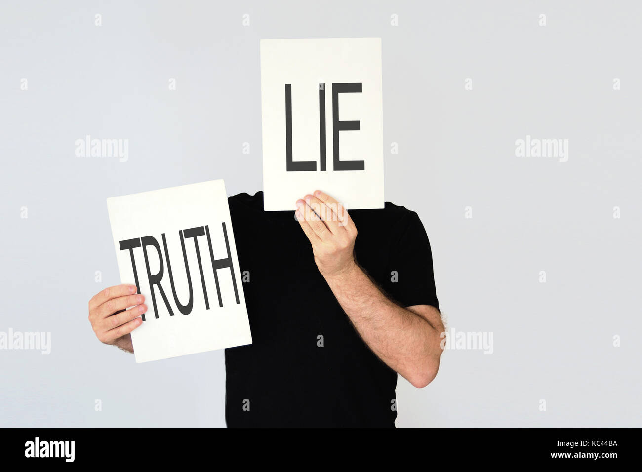Man holding two cards with the words Lie and Truth representing different falsehood. Duality concept. Stock Photo