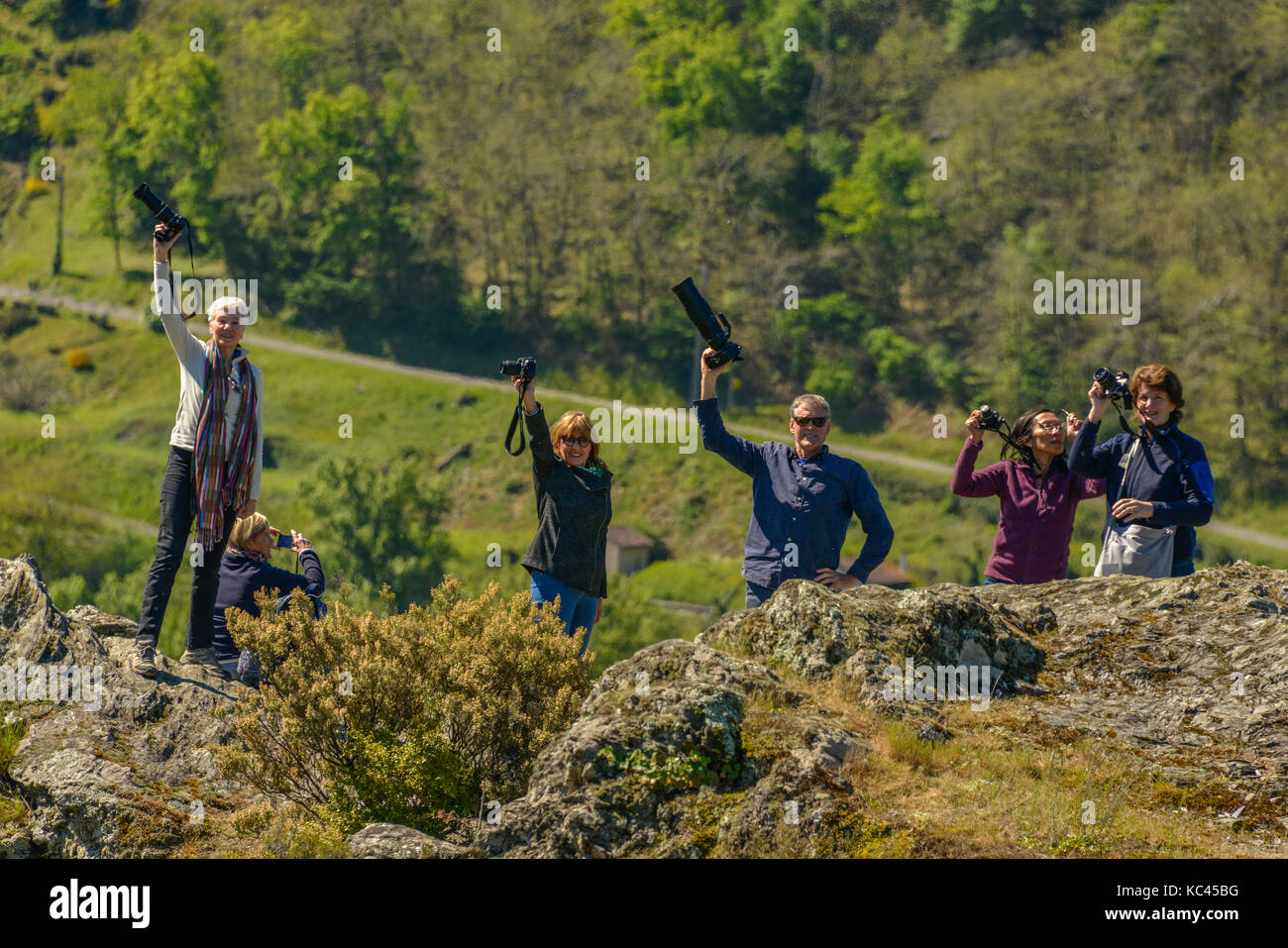 Group of photographers cheering with cameras held high, set against a such rural setting. Stock Photo