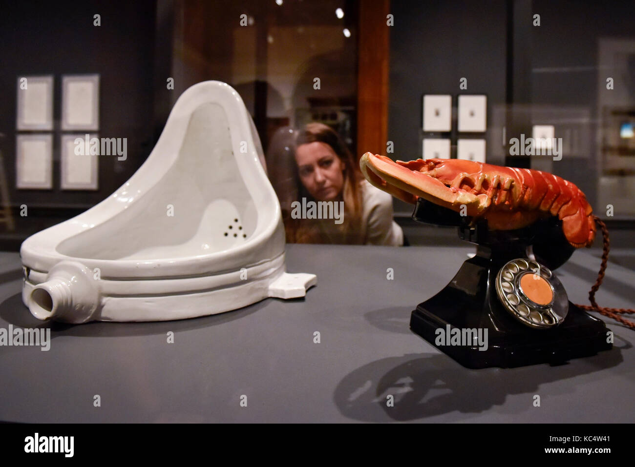London, UK.  3 October 2017.  A staff member views (L to R) 'Fountain, 1917', 1964 edition, by Michel Duchamp and 'Lobster Telephone (red)', 1938, by Salvador Dali with Edward James at the preview of 'Dali / Duchamp', a new exhibition of works by Salvador Dali and Michel Duchamp taking place at the Royal Academy of Arts in Piccadilly.  Over 80 artworks in different media are on display from 7 October to 3 January 2018. Credit: Stephen Chung / Alamy Live News Stock Photo