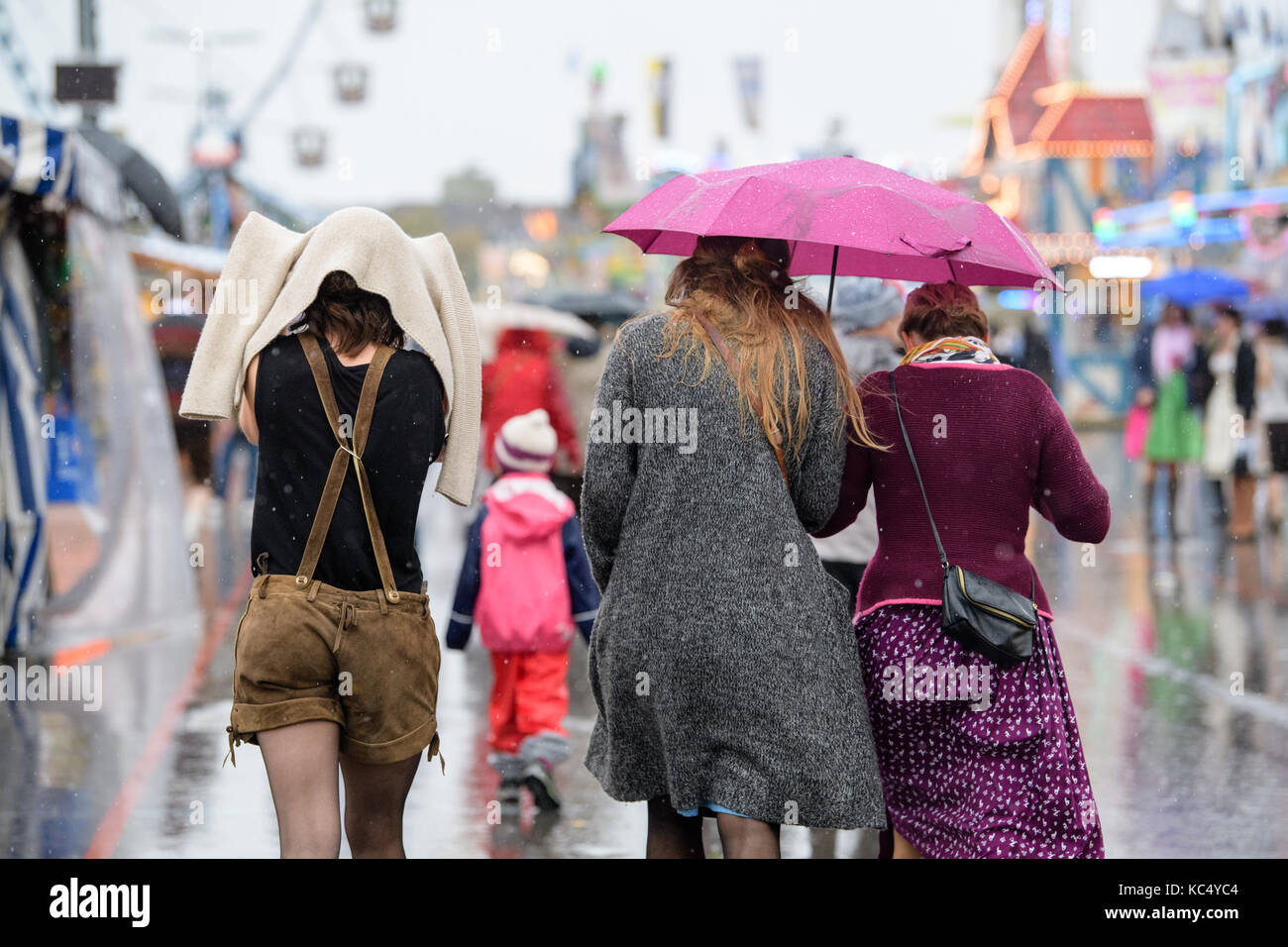 Visitors of the Oktoberfest run across the Oktoberfest fun fair grounds in the rain on the Theresienwiese meadow in Munich, Germany, 03 October 2017. After 18 days, the 184th Oktoberfest ends on 03 October 2017. Photo: Matthias Balk/dpa Stock Photo