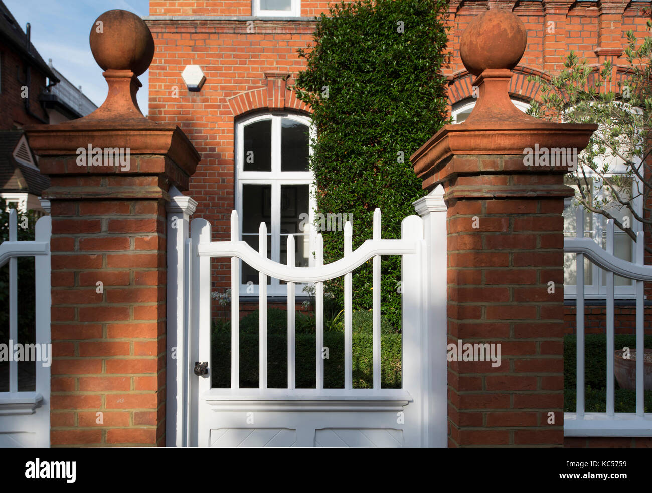 Ball finials on brick pillars and a wooden gate in front of a house