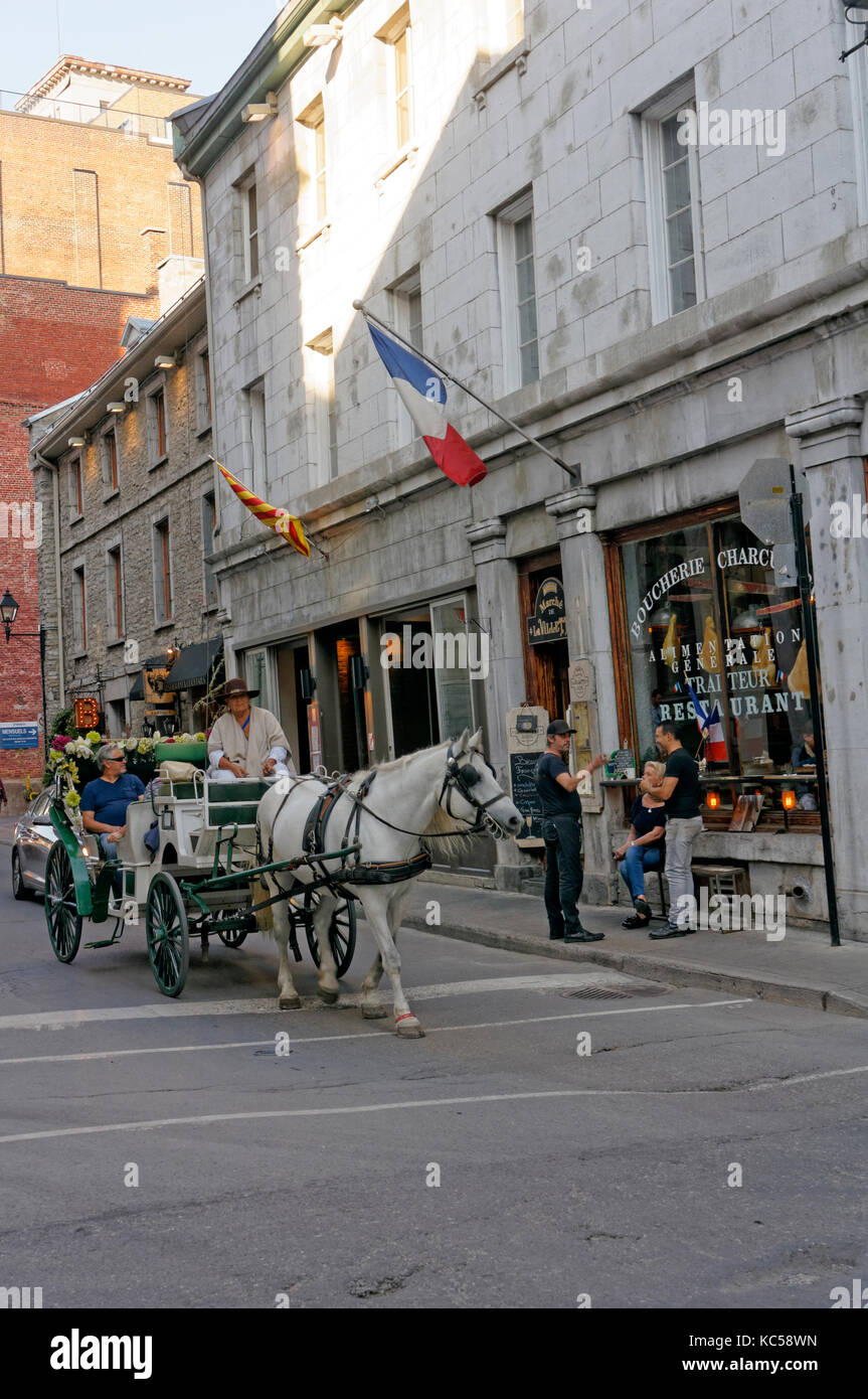 Tourists riding in a horsedrawn carriage or caleche on a street in Old