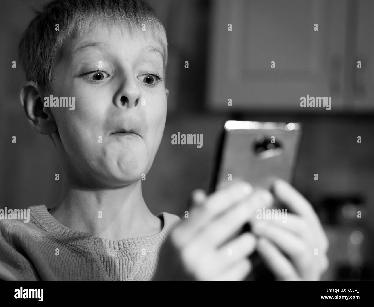 Surprised caucasian boy  with mobile phone. Black and white Stock Photo